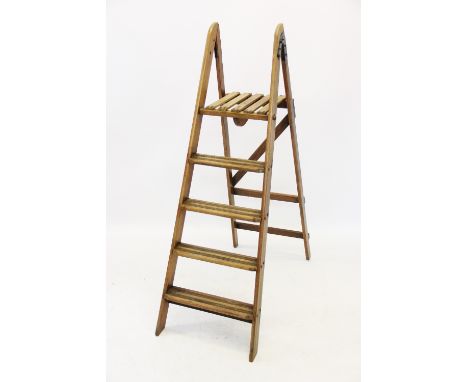 An early 20th century step ladder, of typical 'A' form, with painted iron hinges and a slatted top step, 153cm high 