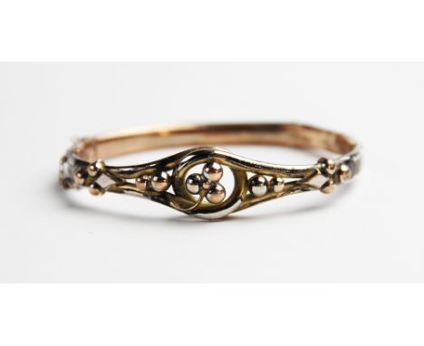 A Victorian yellow metal hinged bangle, the front section designed as a three-leaf clover to a twisted border surround with a