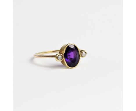 An amethyst and pearl dress ring, comprising a central oval mixed cut amethyst measuring 9mm x 6mm, with a small cultured pea