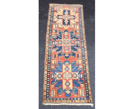 A Caucasian wool runner, the three central geometric medallions in alternating shades of red, blue and taupe, enclosed by rep