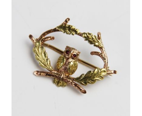 A 9ct gold ruby set owl brooch by Cropp &amp; Farr, designed as an owl sitting amongst oak branches with ruby cabochons set t