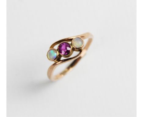 A ruby and opal three-stone ring, comprising a central round mixed cut ruby measuring approx. 4mm diameter, with a round opal