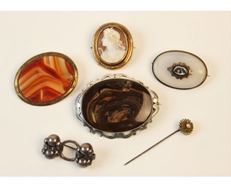 A selection of Victorian and later brooches and pins, to include an oval chalcedony example with a central carved hardstone p