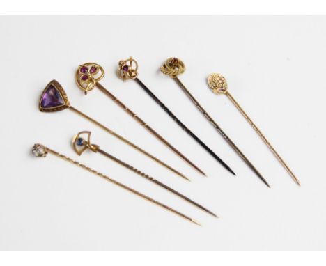 A selection of seven gold and yellow metal stick pins, to include a 14ct gold amethyst set example, 6.2cm long, a yellow gold