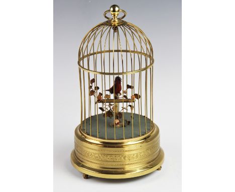 A 20th century French lacquered brass bird automaton, the bird within a domed cage and supported upon a perch with foliage, c