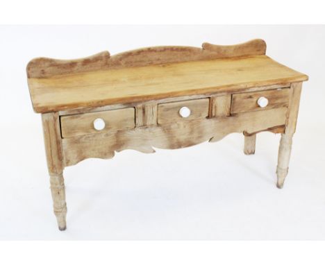 A Victorian pine serving table/dresser, with a shaped raised back above a rectangular slab top and three frieze drawers, each