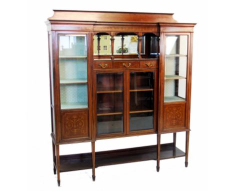 An Edwardian inlaid mahogany inverted breakfront display cabinet, the shaped pediment above a central mirror back arcaded rec