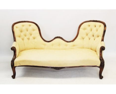 A Victorian rosewood framed double ended chaise longue, the twin arched button back above a serpentine sprung seat, embraced 