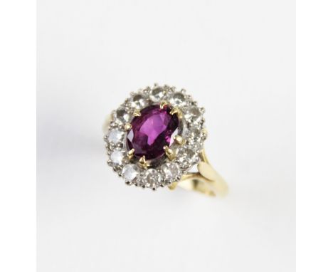 A pink stone and diamond cluster ring, comprising a central untested oval mixed cut stone (probably a pink sapphire) measurin