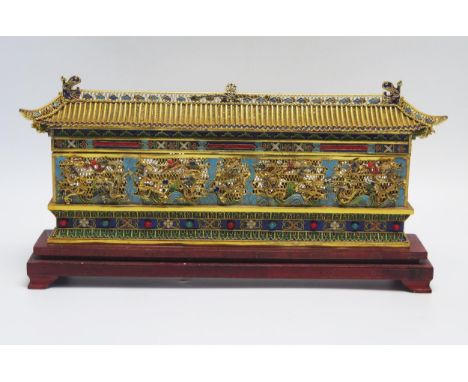A Chinese gilt metal and enamel nine dragon temple, with pitched roof, pierced sides with decorative dragons, on a polished w