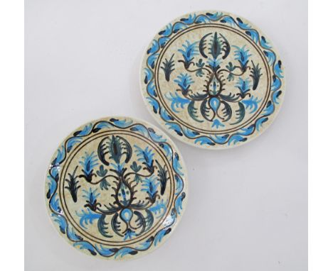 A pair of Greek Keramikos ceramic chargers hand decorated with blue and green foliage W33cm and W30cm, signed with initials b