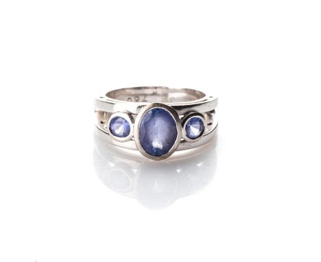 A TANZANITE RING Set to the centre with a bezel-set oval tanzanite, weighing approximately 1,8ct, flanked on either side by t