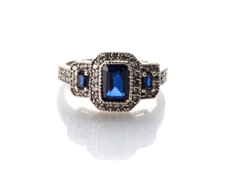 A DIAMOND AND  SAPPHIRE RING Bezel-set to the centre with an emerald-cut sapphire weighing approximately 1,10ct, flanked by t