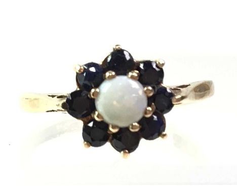 OPAL AND GEMSTONE RING, IN NINE CARAT GOLD the round opal surrounded with eight blue stones in a flowerhead formQty: 1.7g
