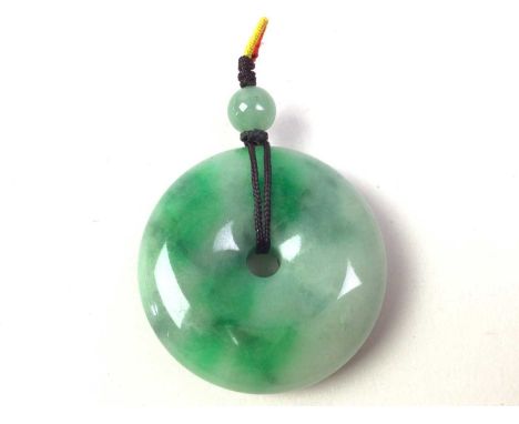 JADE PENDANT, of donut form, beneath a smaller jade bead