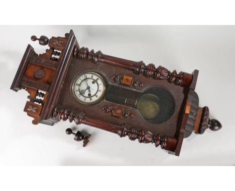 Early 20th Century mahogany cased Vienna wall clock, the pediment top flanked by finials over a white enamel clock face with 