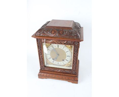 Lenzkirch walnut cased mantel clock, the foliate scroll carved pediment above an acanthus leaf and foliate carved glazed door