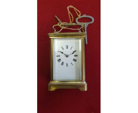 A brass carriage clock, with white enamel dial, the movement striking on a gong.