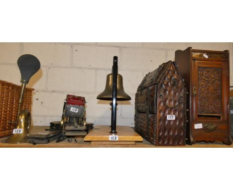 A smokers cabinet with carved panel door (in need of repair), a bell suspended from metal supports on wooden base, a reproduc