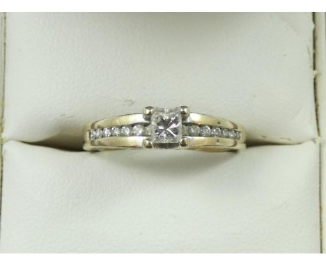 An 18ct gold single stone diamond ring, claw set with a Princess cut stone, weighing approximately 0.30 cts, diamond set shou