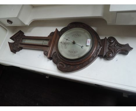 An early 20th century mahogany frame aneroid barometer having carved pediment and bezel, with thermometer scale