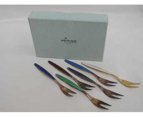 A boxed set of six Norwegian silver and enamel cake forks of different colours, retailed by Magnus Aase of Bergen