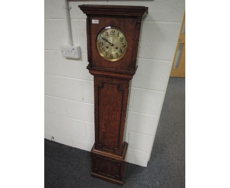 An early 20th century oak granddaughter clock having square pillar containing circular silvered dial on beaded trunk and squa