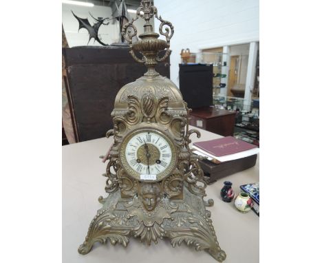 An early 20th century brass mantel clock in cast Rococco style having ornate decoration and striking mount