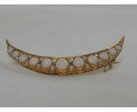 An early 20th century  opal and diamond crescent brooch having eleven graduated cabouchon opals interspersed by pairs of diam