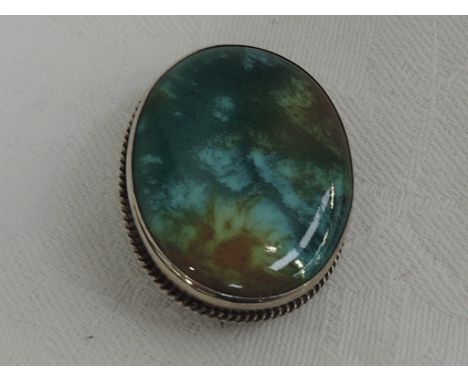 An Edwardian brooch having an Arts & Crafts style mottled green and mustard coloured ceramic panel in a silver mount having r