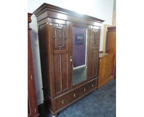 A 1920's Waring & Gillows oak wardrobe having central mirror door and drawers under on bun feet