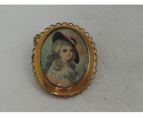 A yellow metal brooch stamped 9ct having a ceramic panel depicting a maiden in profile