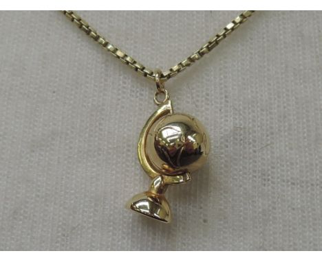 A yellow metal pendant in the form of a globe on a yellow metal box chain stamped 375