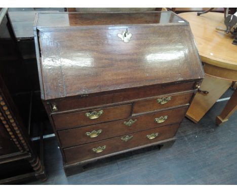 An early 19th century oak bureau having slope front with fitted interior and concealed section over two short and two long dr