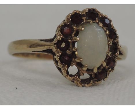 A lady's dress ring having an oval opal and garnet cluster in a raised basket mount on a 9ct gold loop, missing 3 stones 