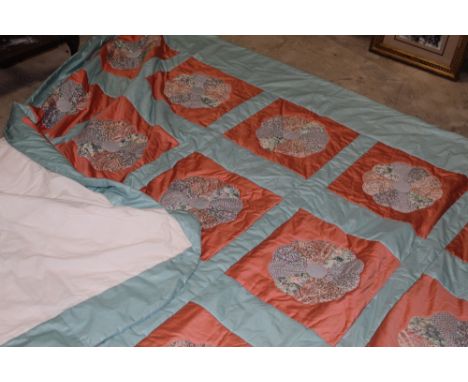 A mid to late 20th century machine worked patchwork quilt decorated with a grid of stylised foliate panels against a light bl