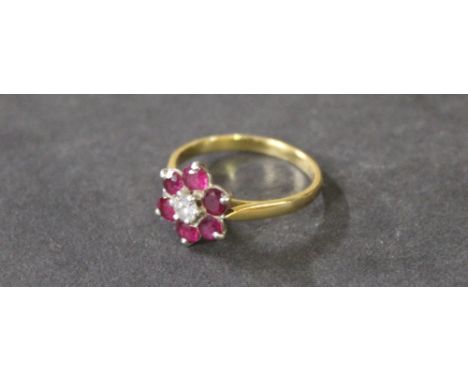 An 18 ct gold platinum set ruby and diamond flower head ring, central brilliant cut diamond measuring .20 carats surrounded b