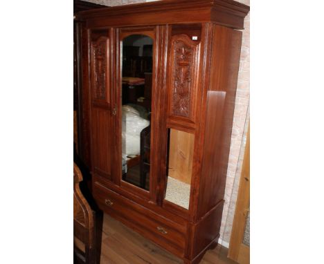 An Edwardian mahogany mirror door wardrobe, having a moulded cornice and plain frieze over the arched central oblong mirror d