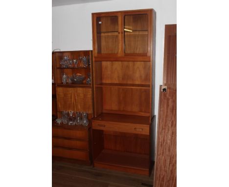 A 1970's teak display cabinet, having two glazed upper doors, over a single open shelf and base section with open base. 209 c