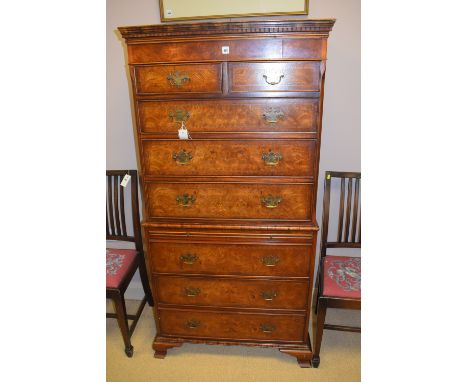 A reproduction figured walnut and elm veneered chest-on-chest, the top with flared dentil cornice above two short and three l