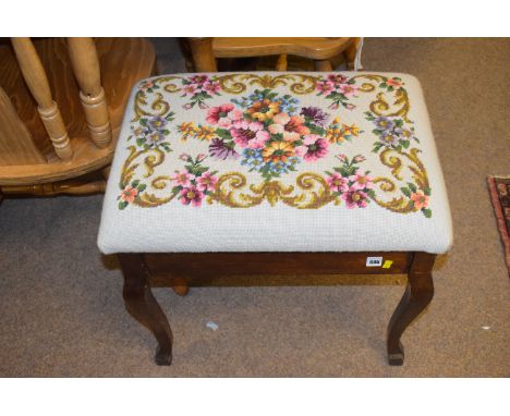 An early 20th Century stained wood piano stool with lift up tapestry work seat.