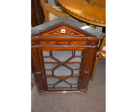 An inlaid mahogany hanging corner cabinet with architectural pediment, the astragal glazed door opening to reveal fabric line