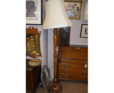 A stained turned wooden standard lamp with modern cream shade.