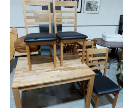 A contempory light oak kitchen table and four ladderback chairs. One chair with damaged seat cushion