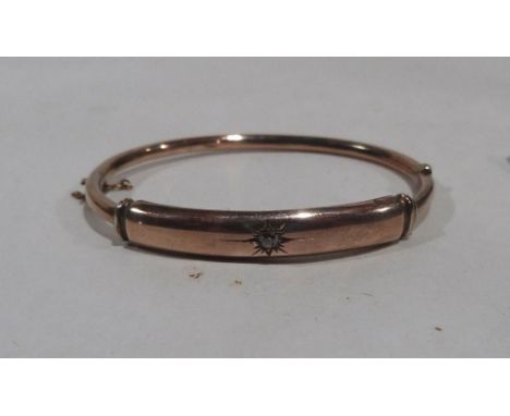 A yellow metal hinged bangle set with a white stone