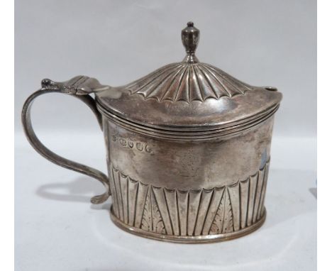 A Victorian silver oval form half-gadrooned mustard, the lid with urn finial, blue glass liner. London 1882. 3¼' high