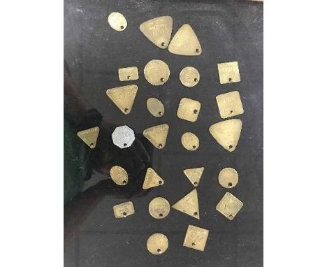 Twenty six miner's lamp checks (tokens or tallies) in a glass display case 