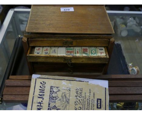 A wooden cased Mahjong set together with instruction book and wooden stands for tiles.