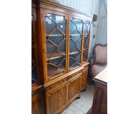 A reproduction mahogany breakfront bookcase, with four astragal glazed doors above four drawers and four panelled doors, rais