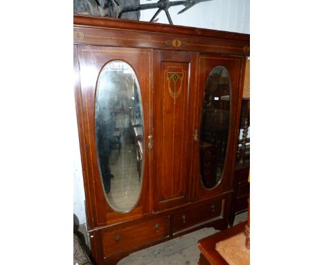 An early 20th Century inlaid mahogany double wardrobe, the central panel with decorative motif, flanked by two doors with bev